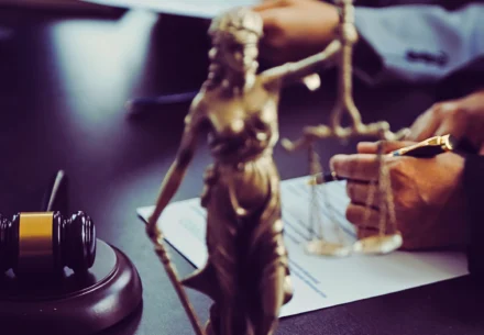 Lady Justice with a hand holding a pen on the background.