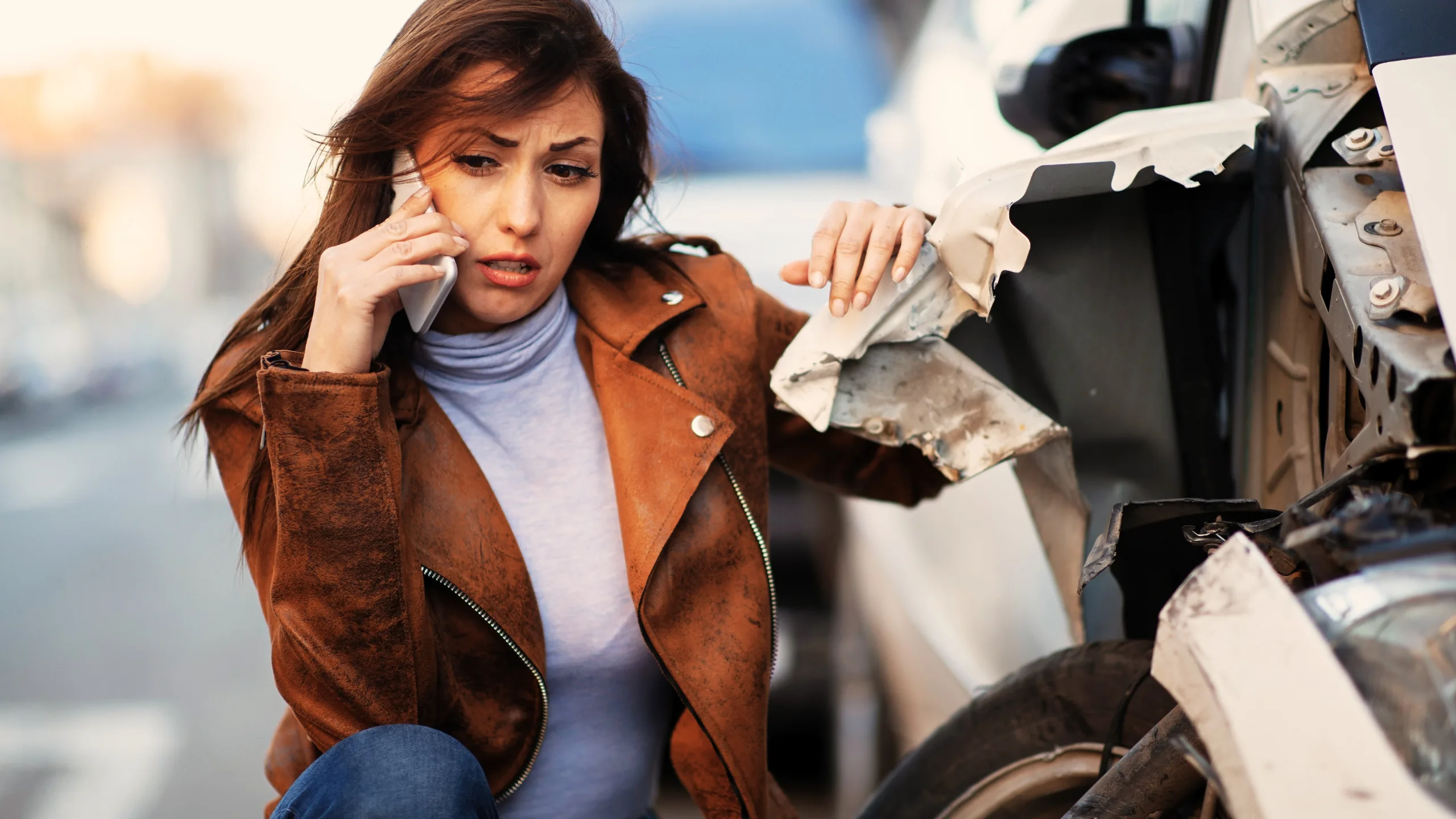 LEGAL GUIDE: WHAT DO YOU DO IF YOU ARE HIT BY A VEHICLE THAT IS STOLEN 1 Worried woman using her phone next to her wrecked car.