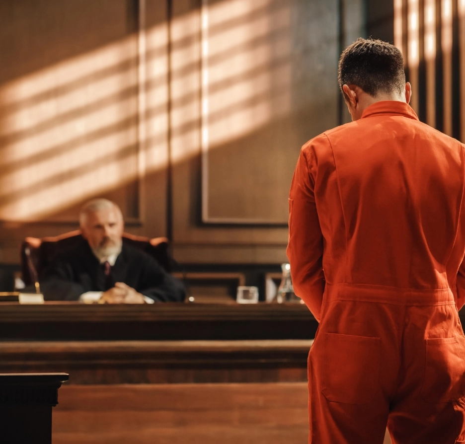 A man in orange jumpsuit faces the judge.