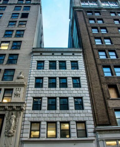 light colored brick building wedged between two taller buildings, law office in NYC