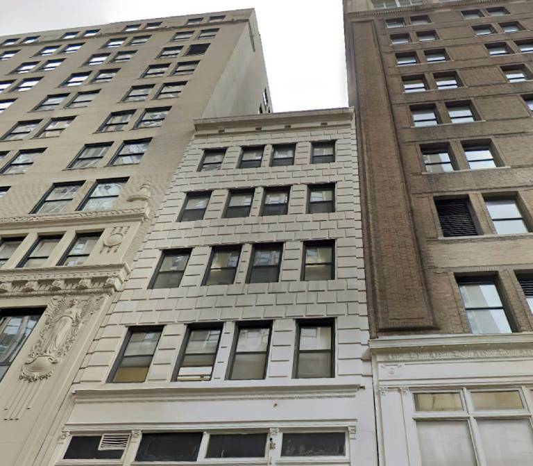 light colored brick building wedged between two taller buildings, law office in NYC