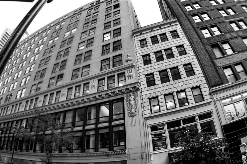 Low-angle fisheye view of towering black-and-white city buildings.