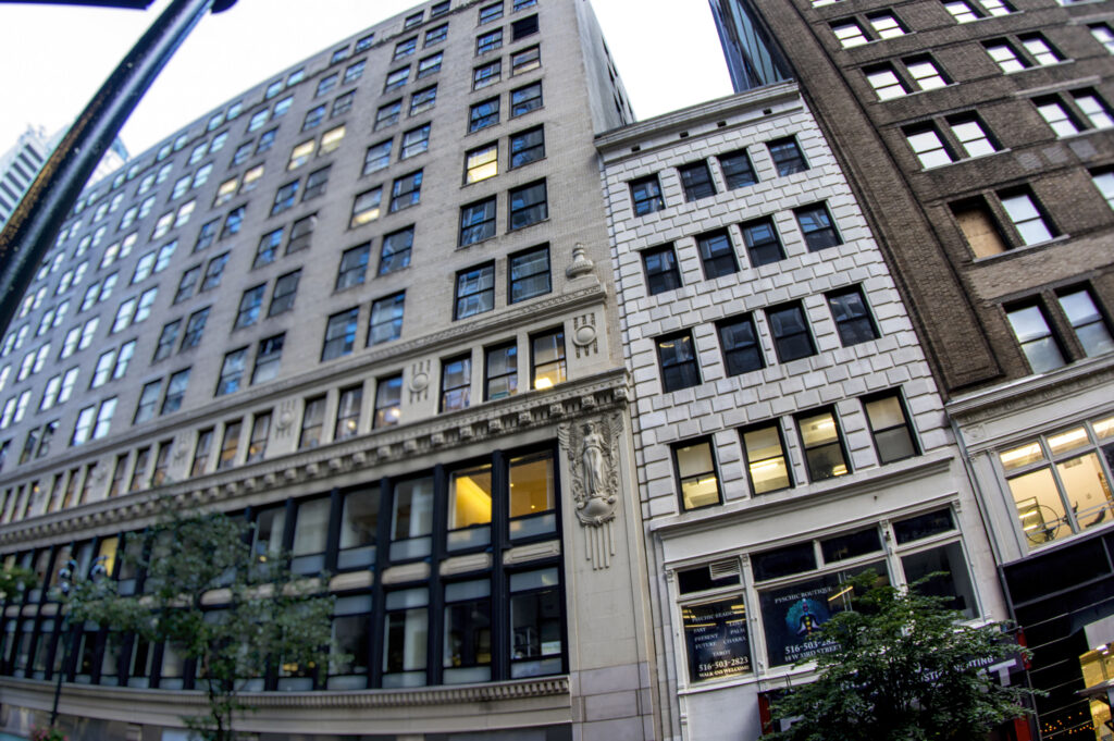 a street-level view of several adjacent multi-story buildings in an urban setting