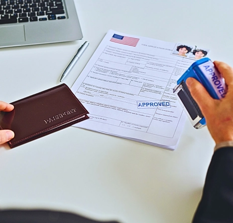 An immigration office worker stamping a visa application form with an "APPROVED" stamp.