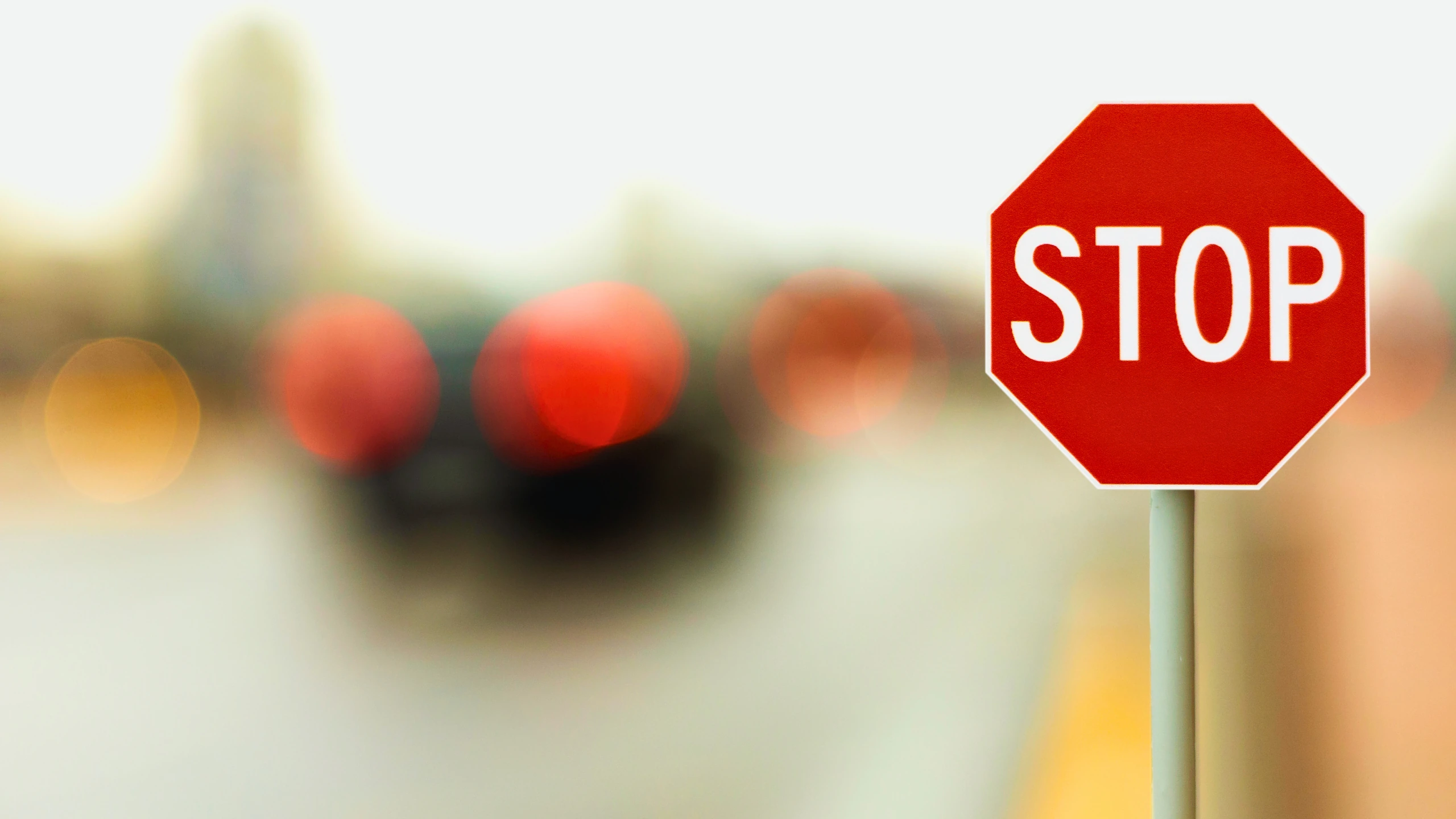A red stop sign on a post against a blurred background of city traffic.