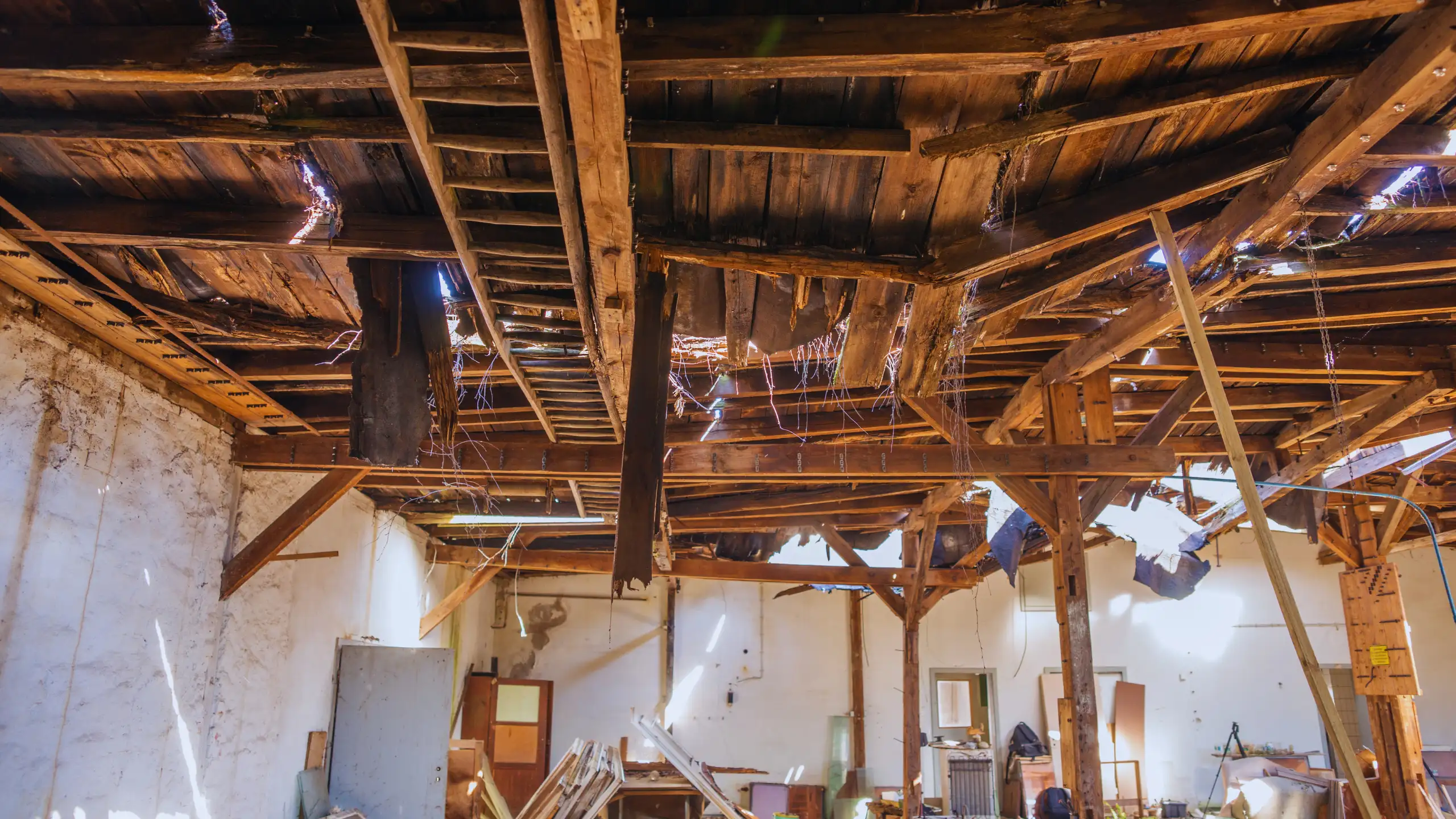 Damaged wooden ceiling in a dilapidated interior space.