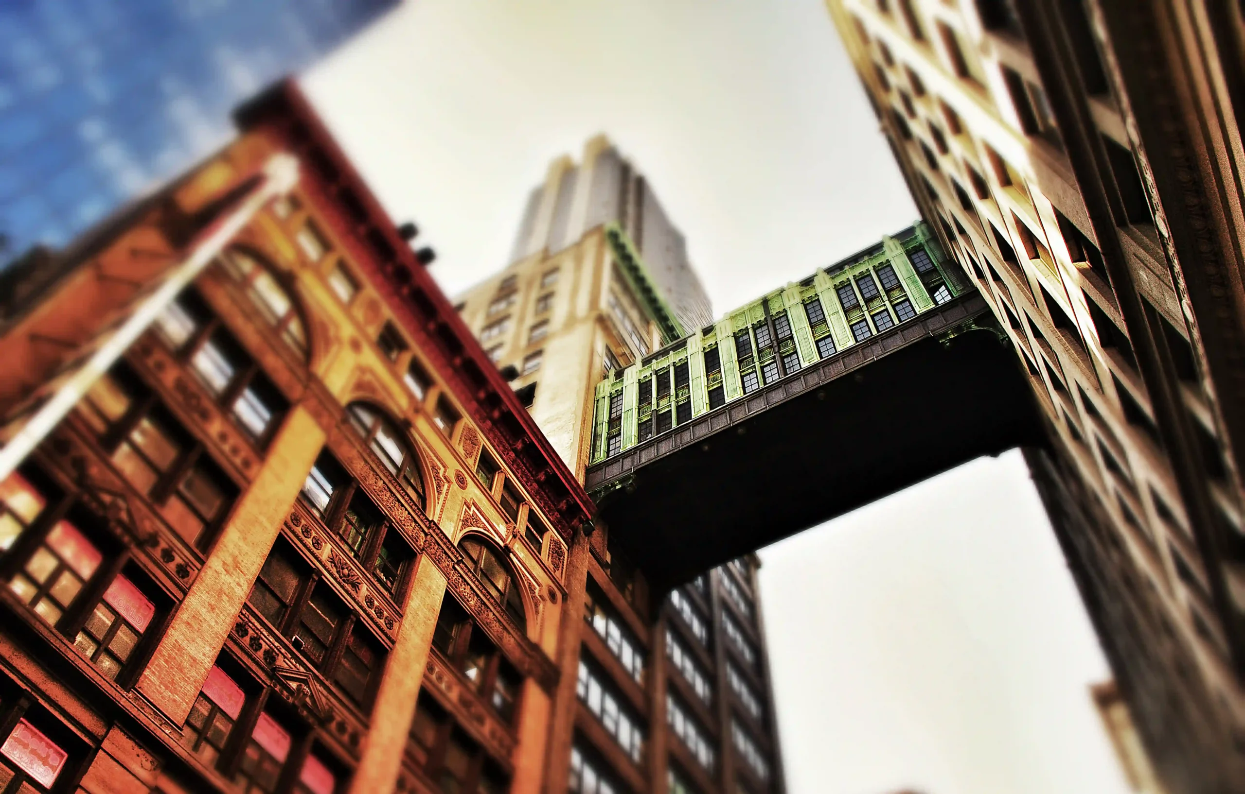 Colorful historic buildings with a skybridge between them, viewed from below.