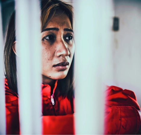 A woman wearing behind metal bars.