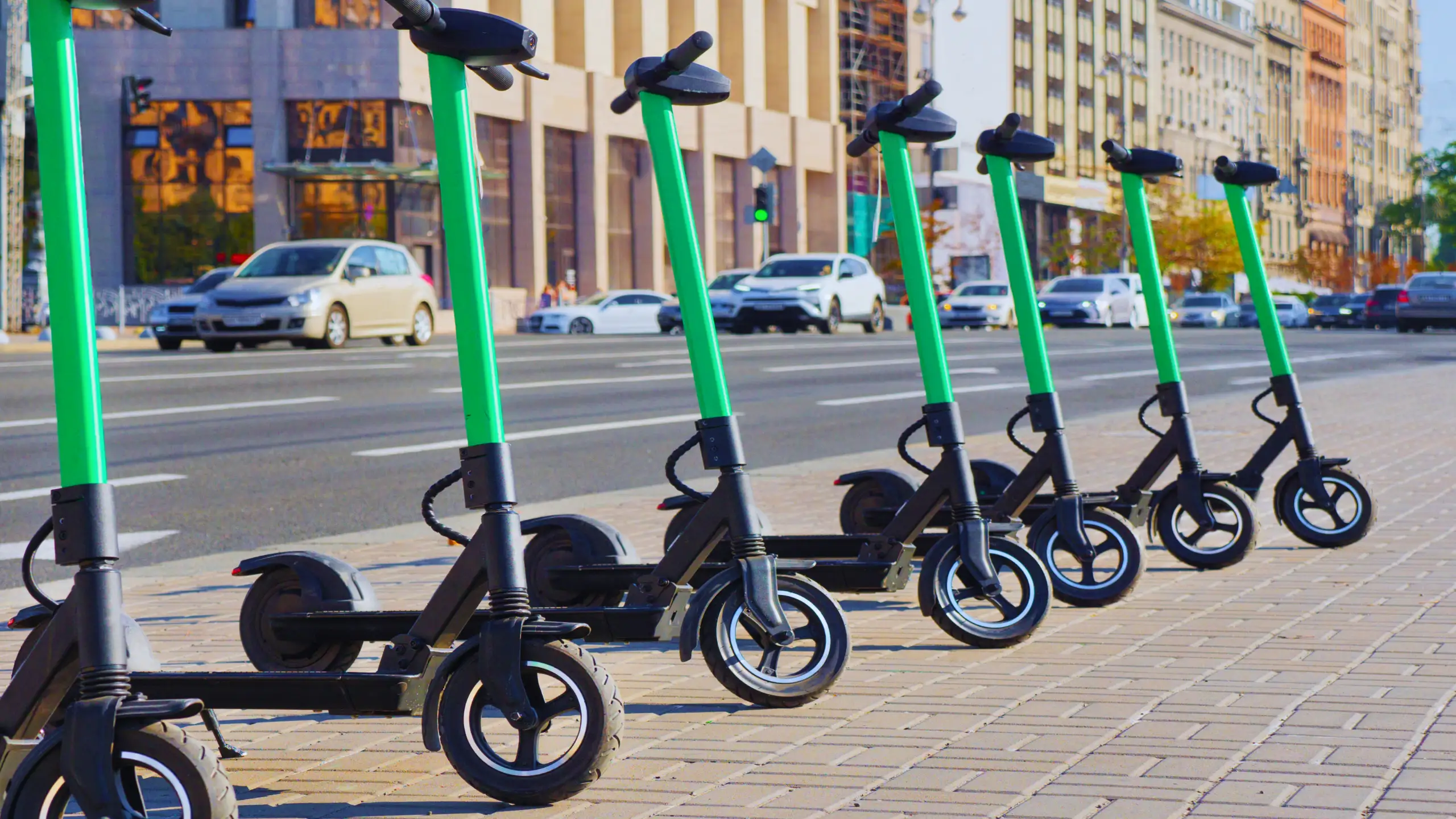 Understanding the Legal Implications of E-bike accidents in NYC 1 Row of green electric scooters parked along a city sidewalk.