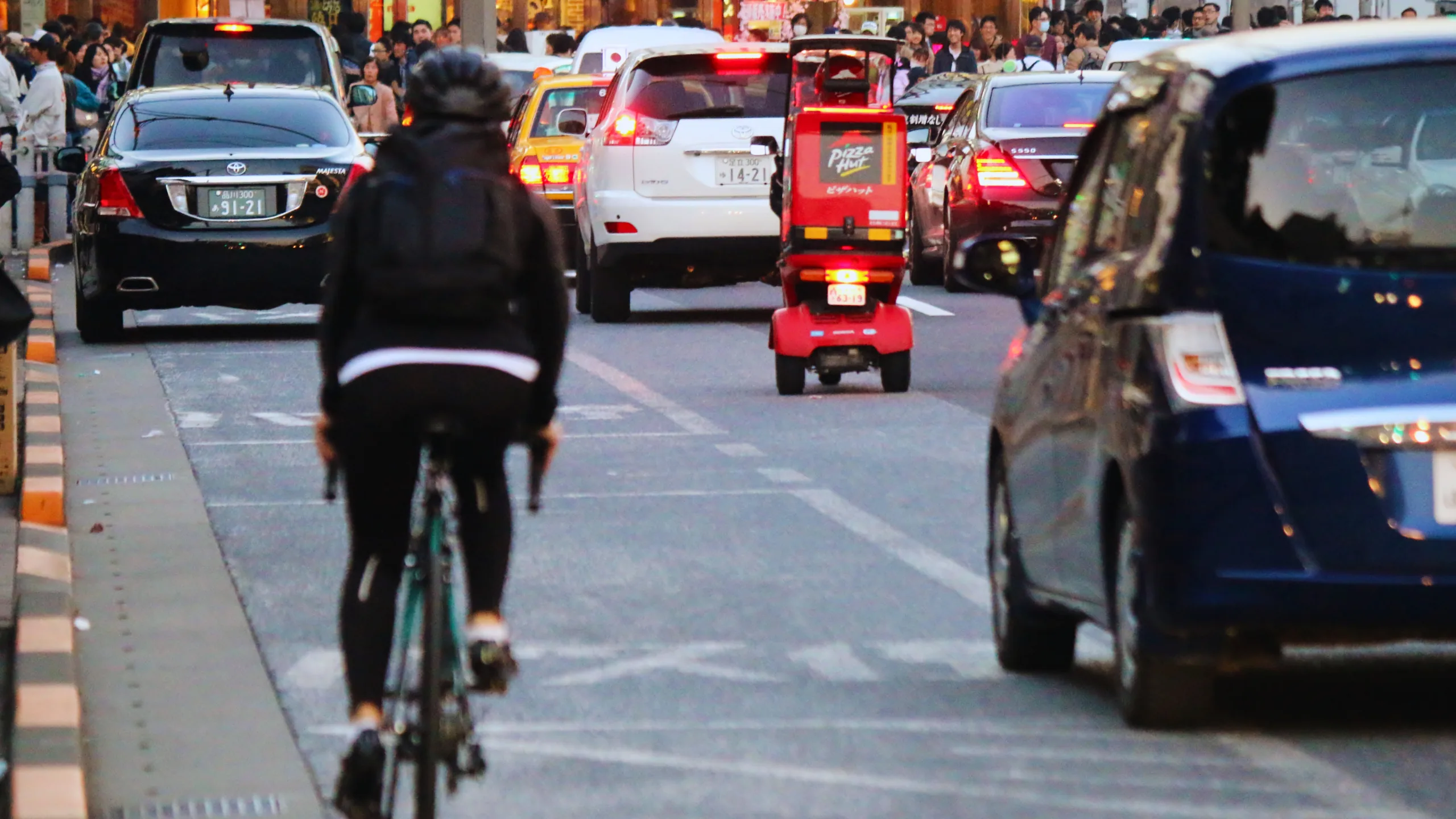 Victory for Bicyclist who got Doored by New York City Police Vehicle 1 A cyclist on a busy city street in traffic, followed by a red pizza delivery.