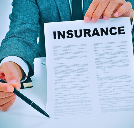 a person in a suit holding up a document titled "INSURANCE" and pointing to it with a pen.